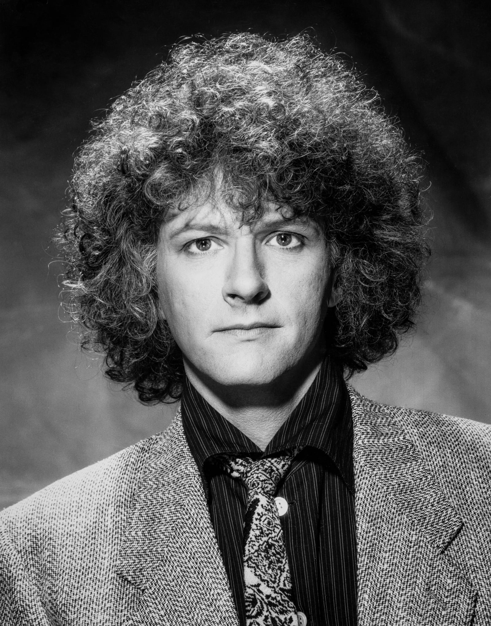 Rama in a tweed jacket and paisley tie, black and white studio portrait