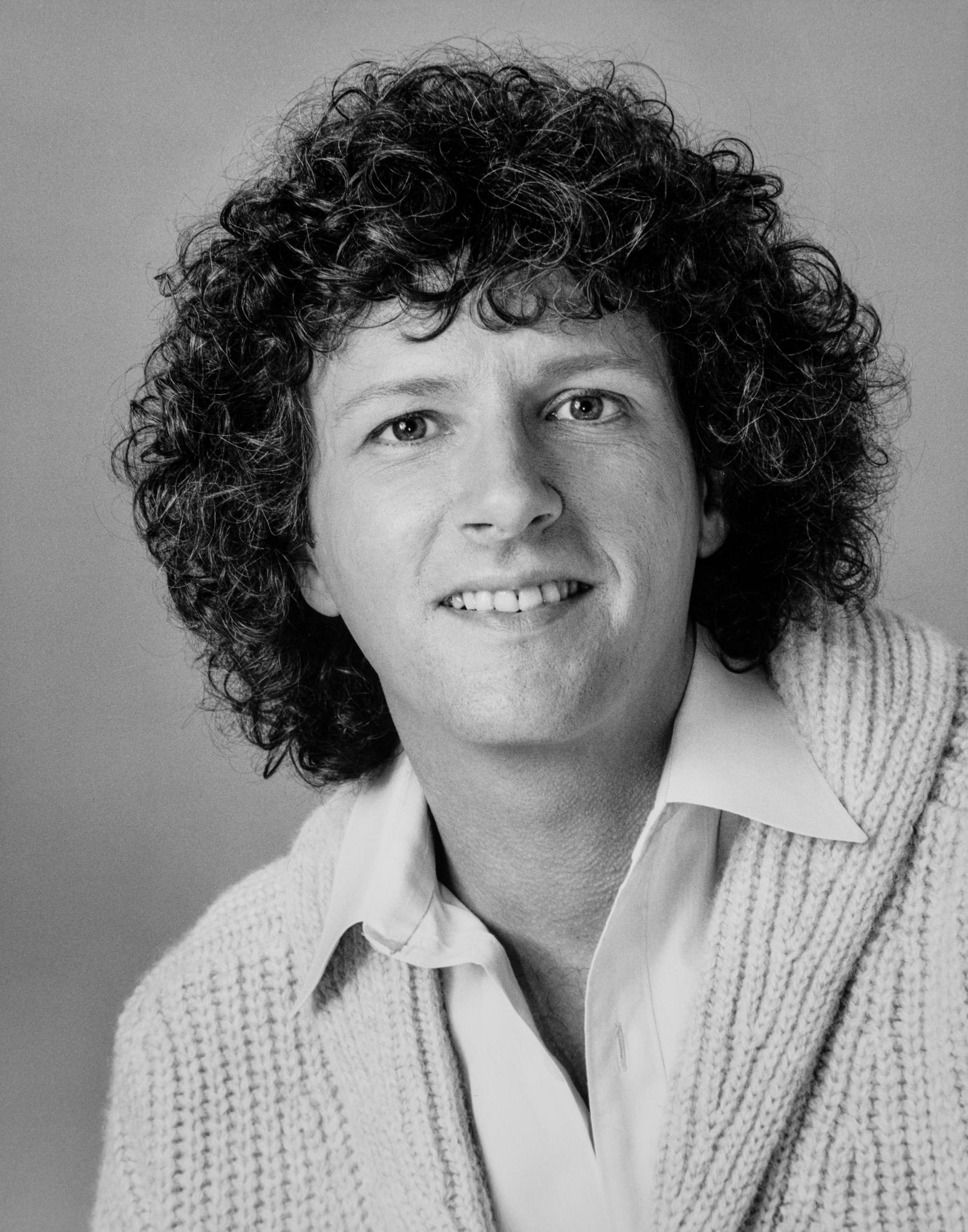 Rama smiling in a cardigan and open collar, black and white portrait