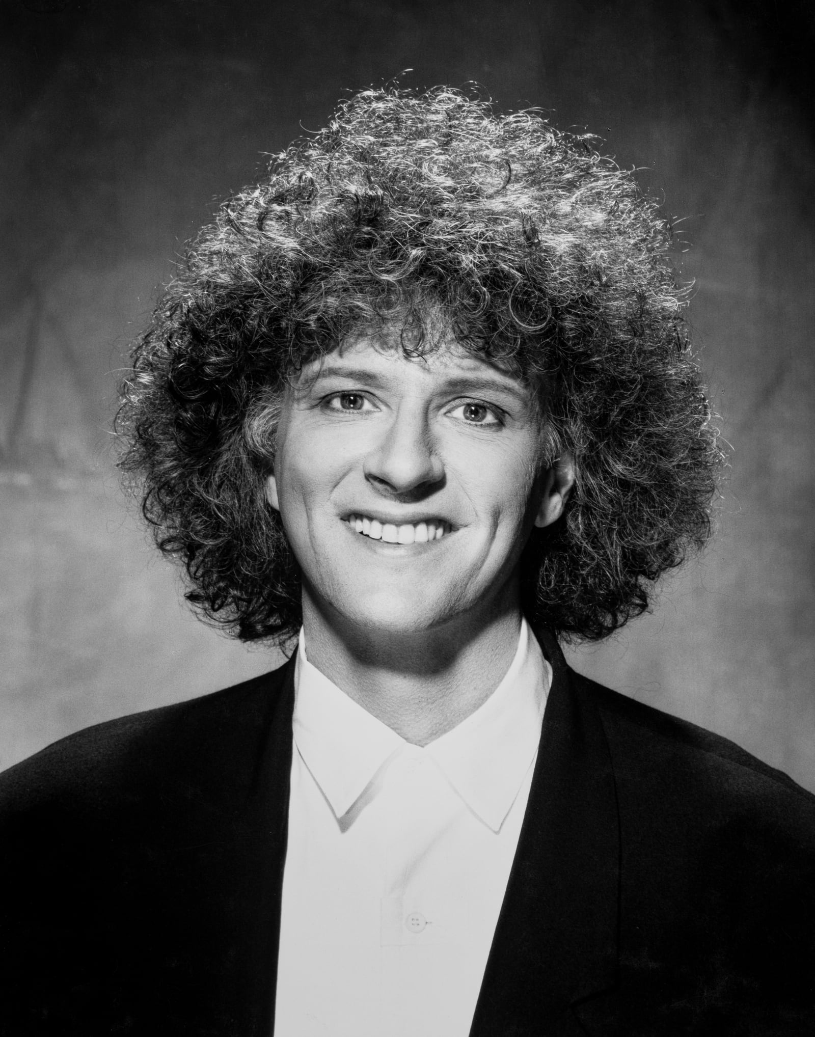Rama laughing in a black jacket and white shirt, black and white portrait