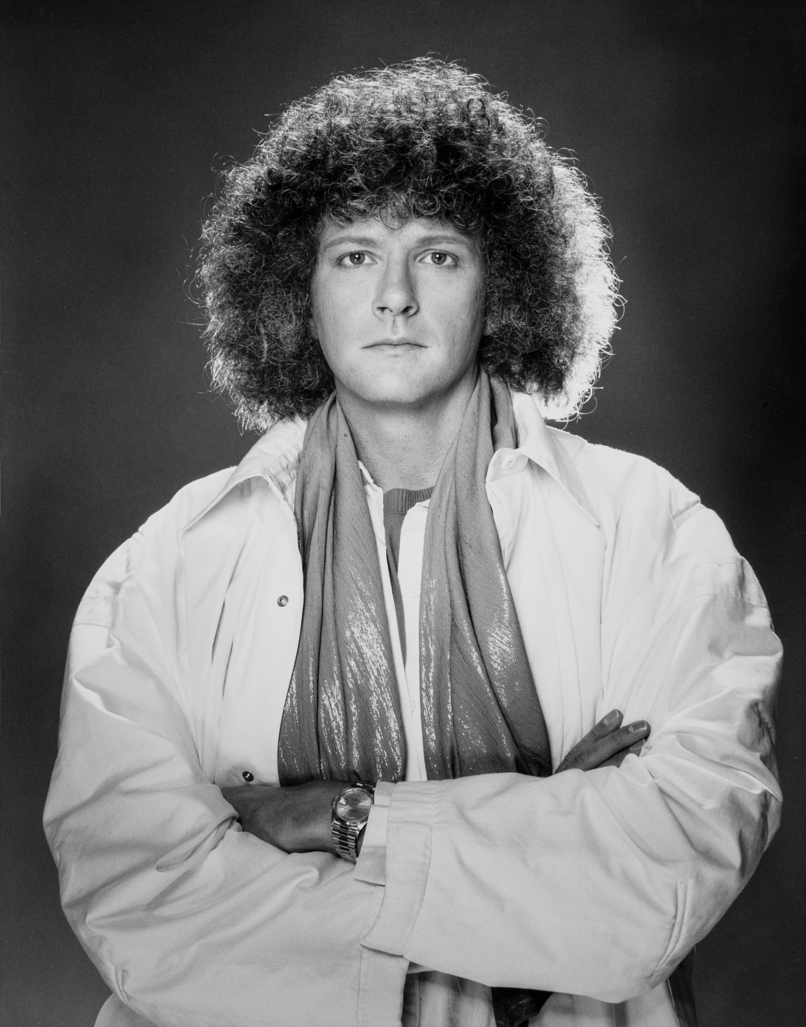 Rama in a white jacket and scarf with arms crossed, black and white studio portrait